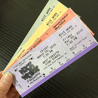 Hand holding multiple printed event tickets showing different formats and designs