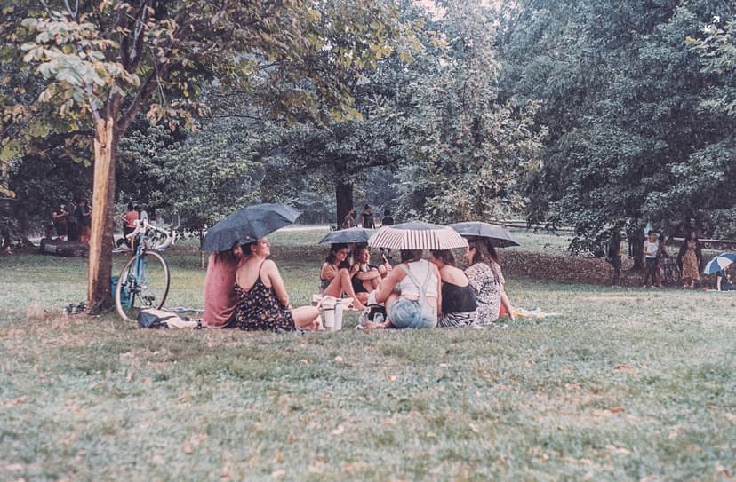 A group of people sitting with umbrellas on.